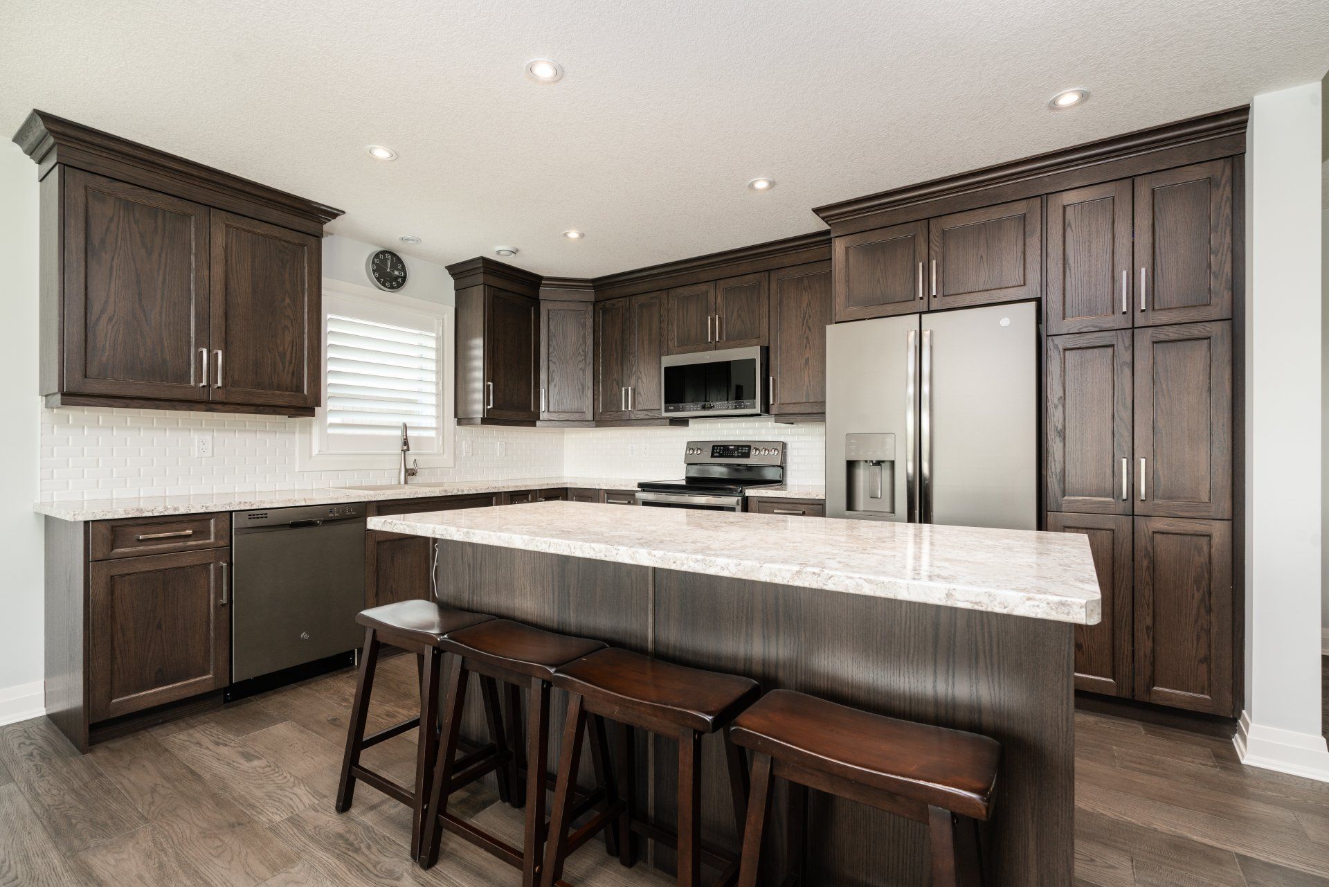 A kitchen with stools and a large island in the middle.