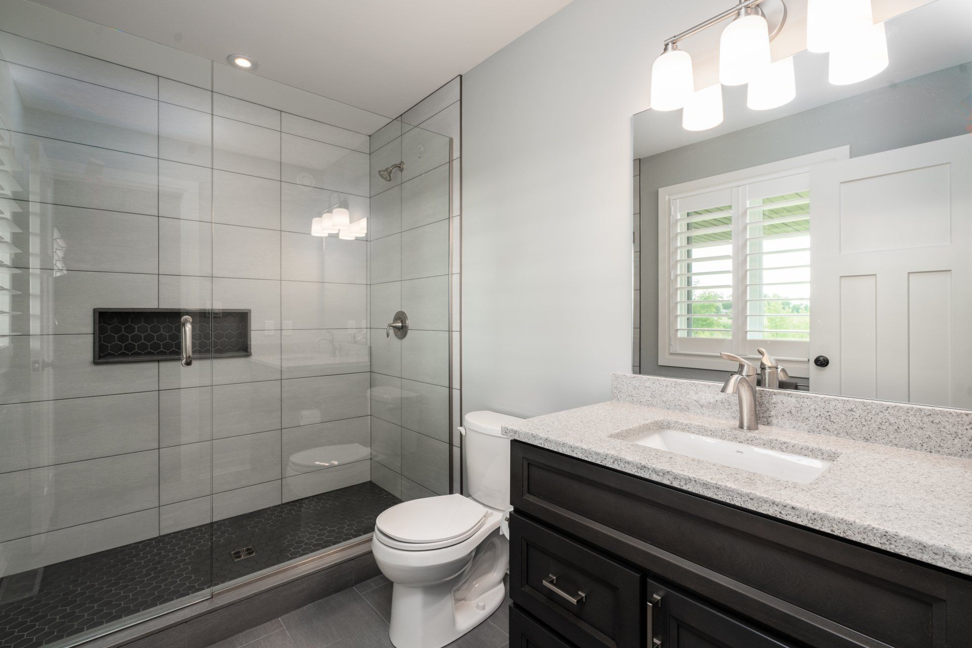 A bathroom with a toilet , sink , mirror and walk in shower.