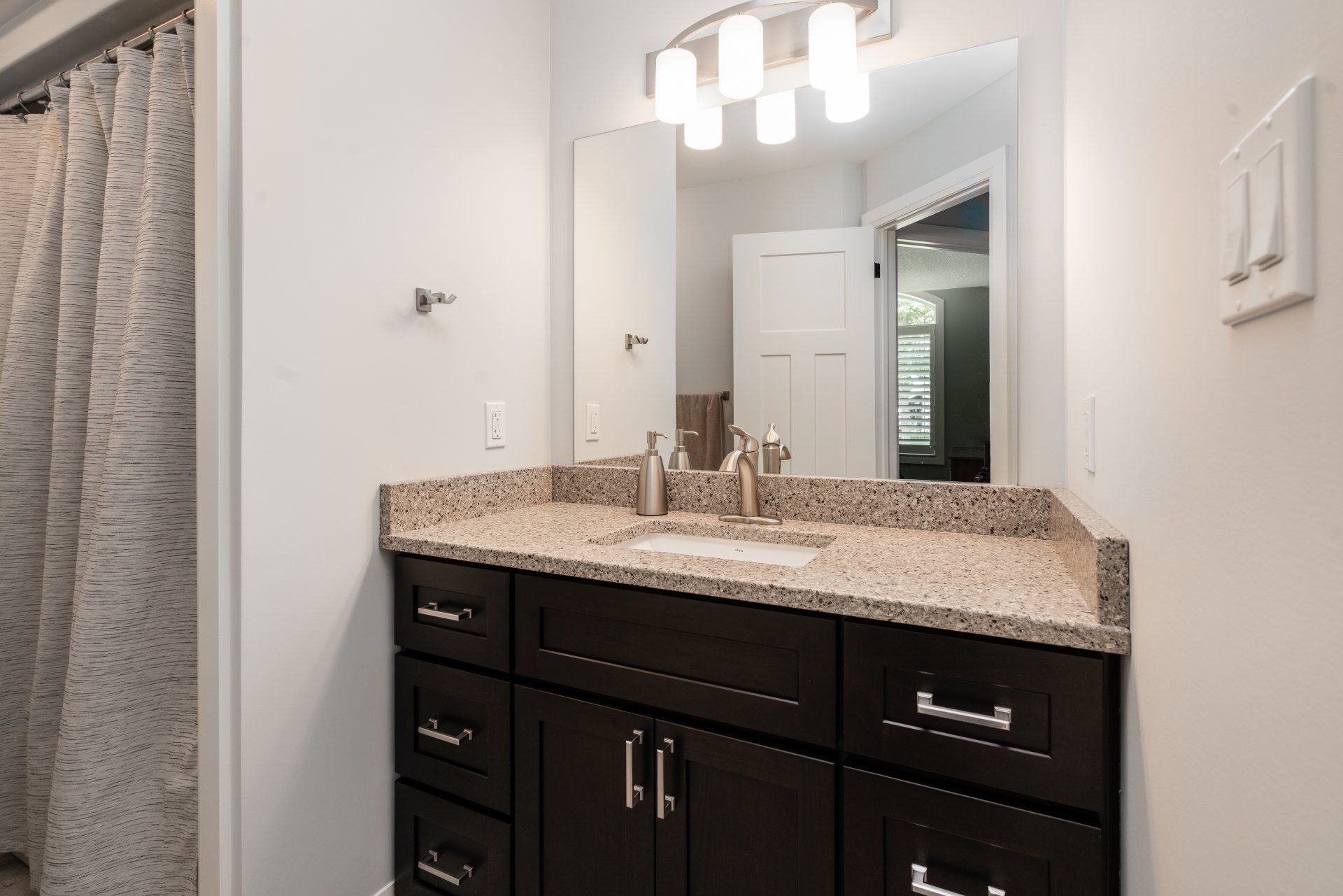 A bathroom with a sink , mirror and shower curtain
