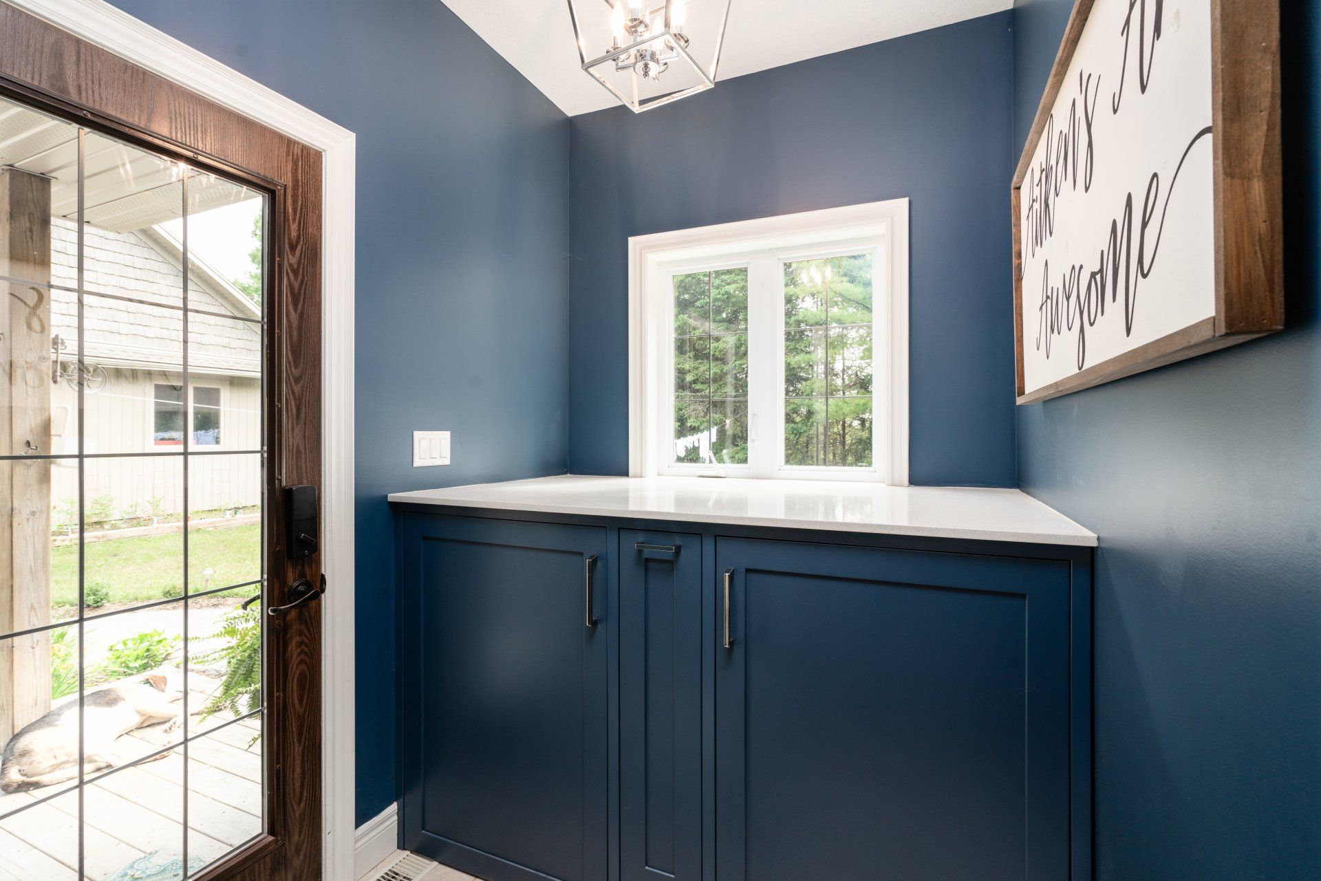 A laundry room with blue cabinets and a sign on the wall.