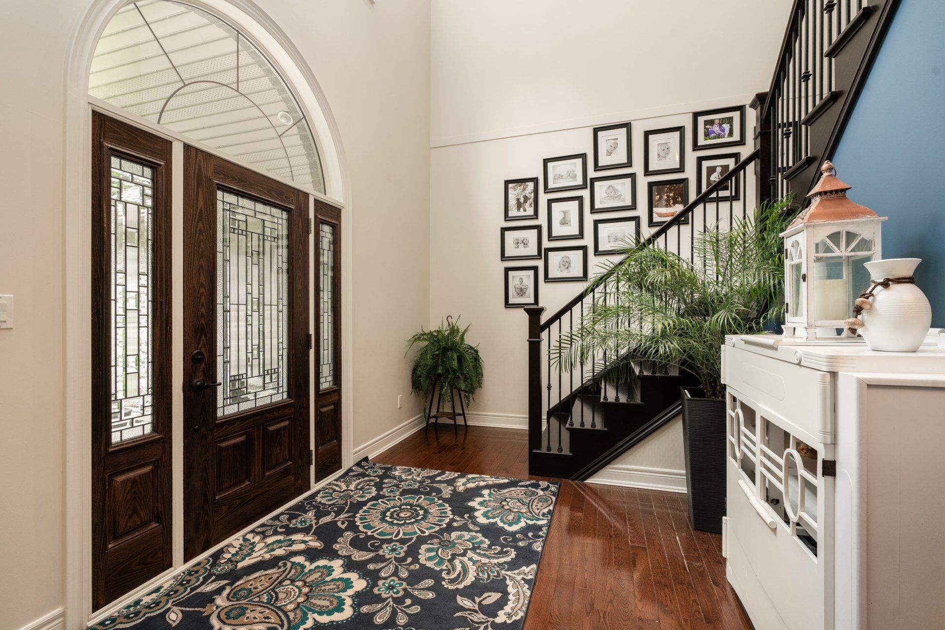 A hallway with a staircase and a rug in a house.