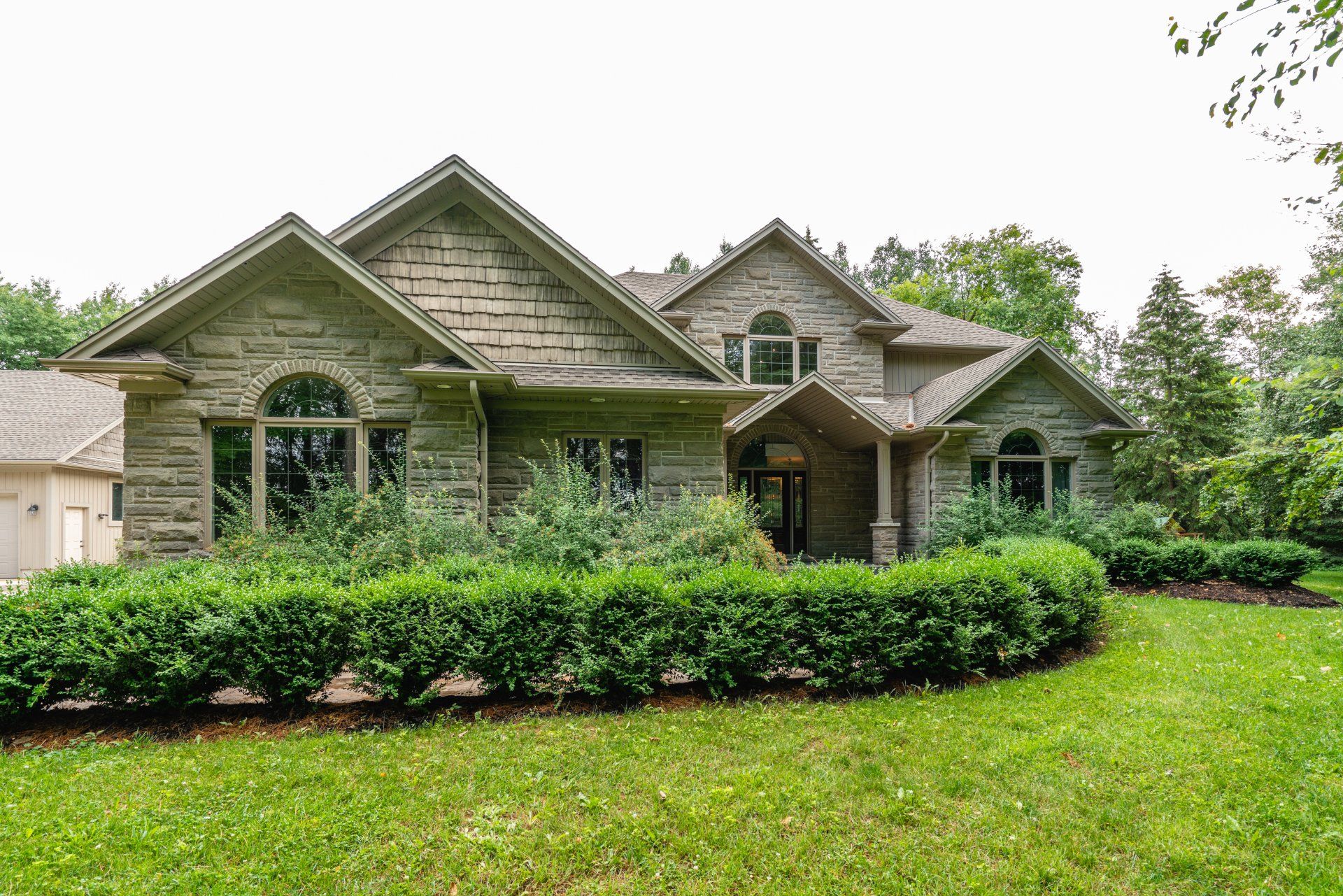 A large house with a lot of windows and bushes in front of it.