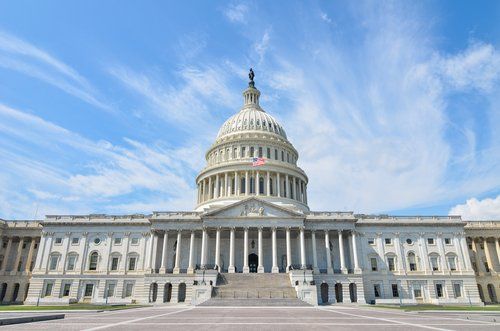 The capitol building in washington d.c. on a sunny day with a blue sky in the background.