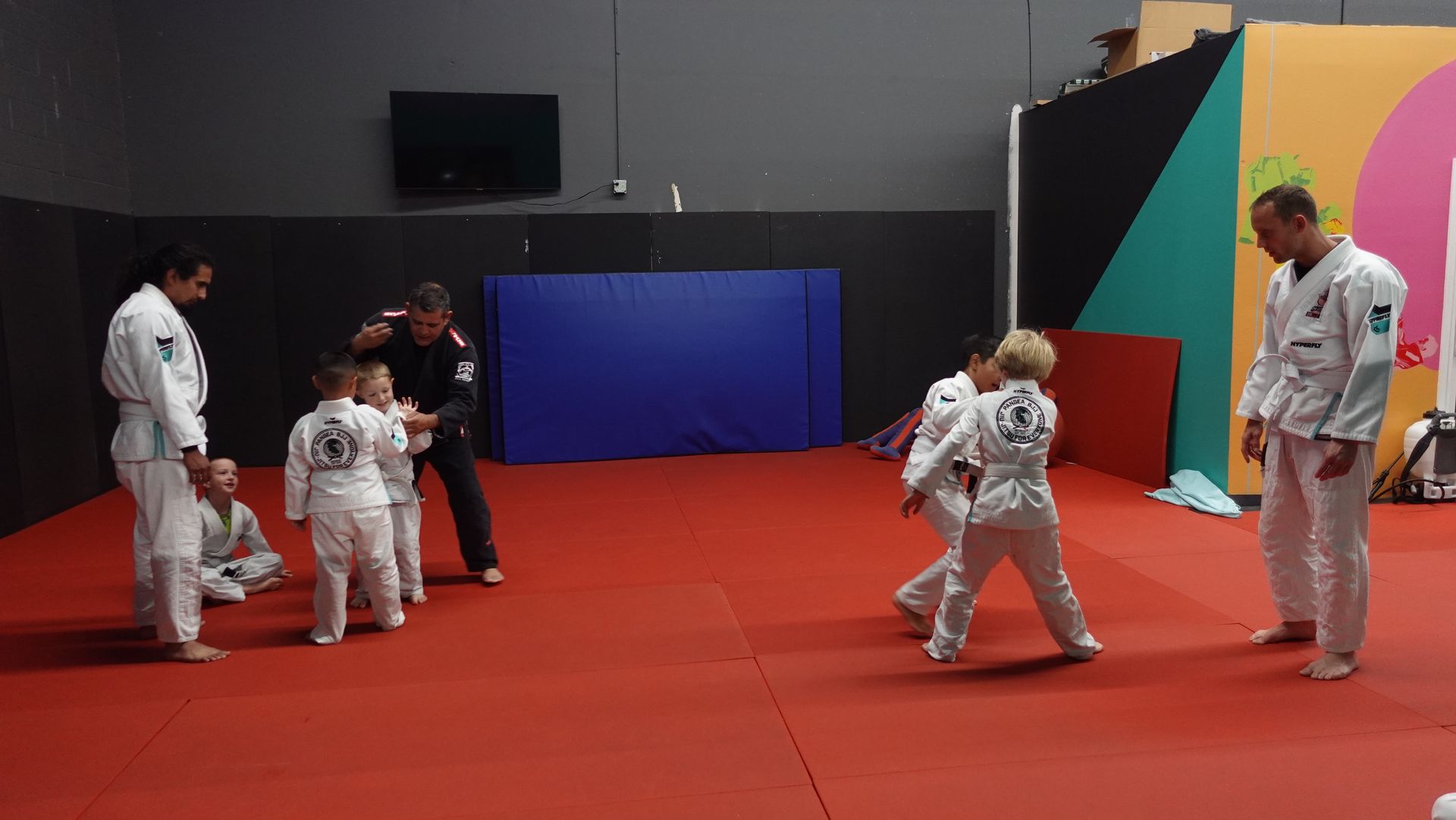 A group of people are standing on a red mat in a gym.