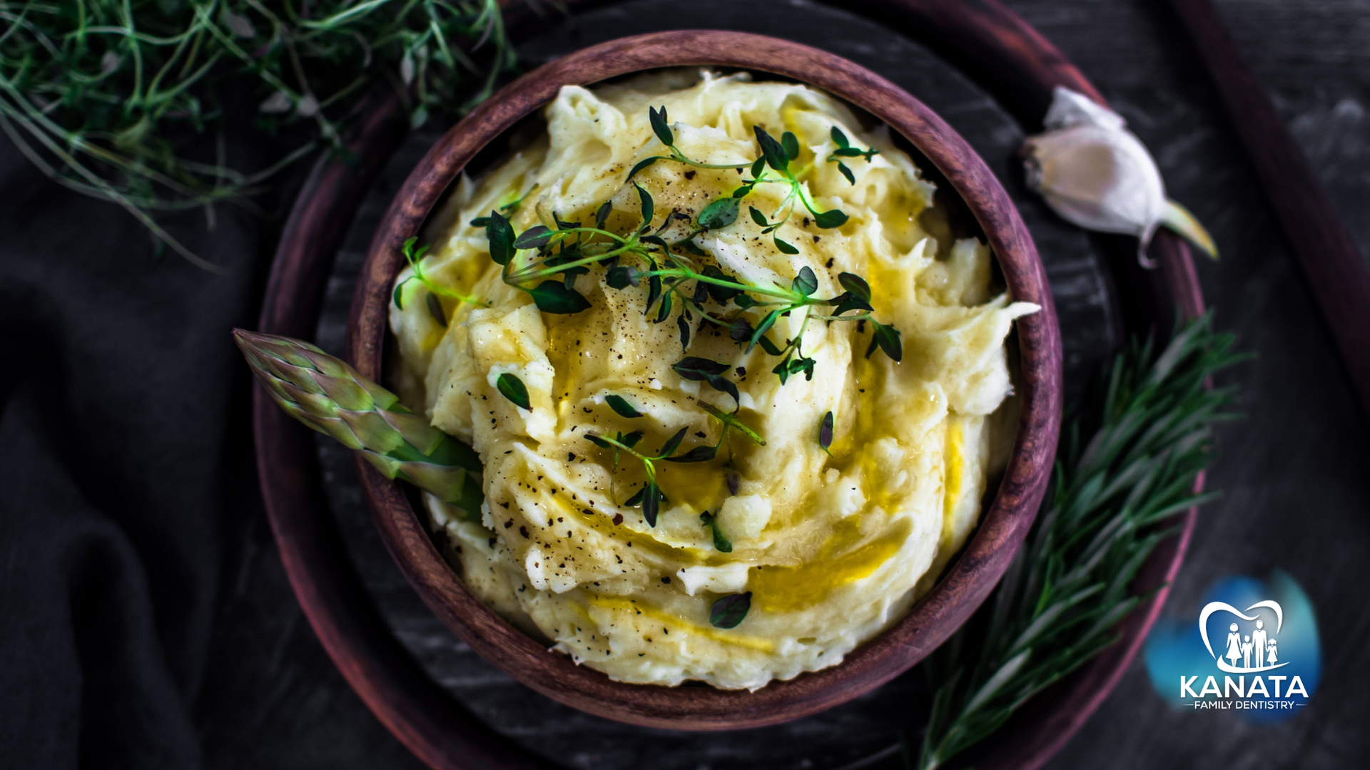 A bowl of mashed potatoes with asparagus and garlic on a plate.