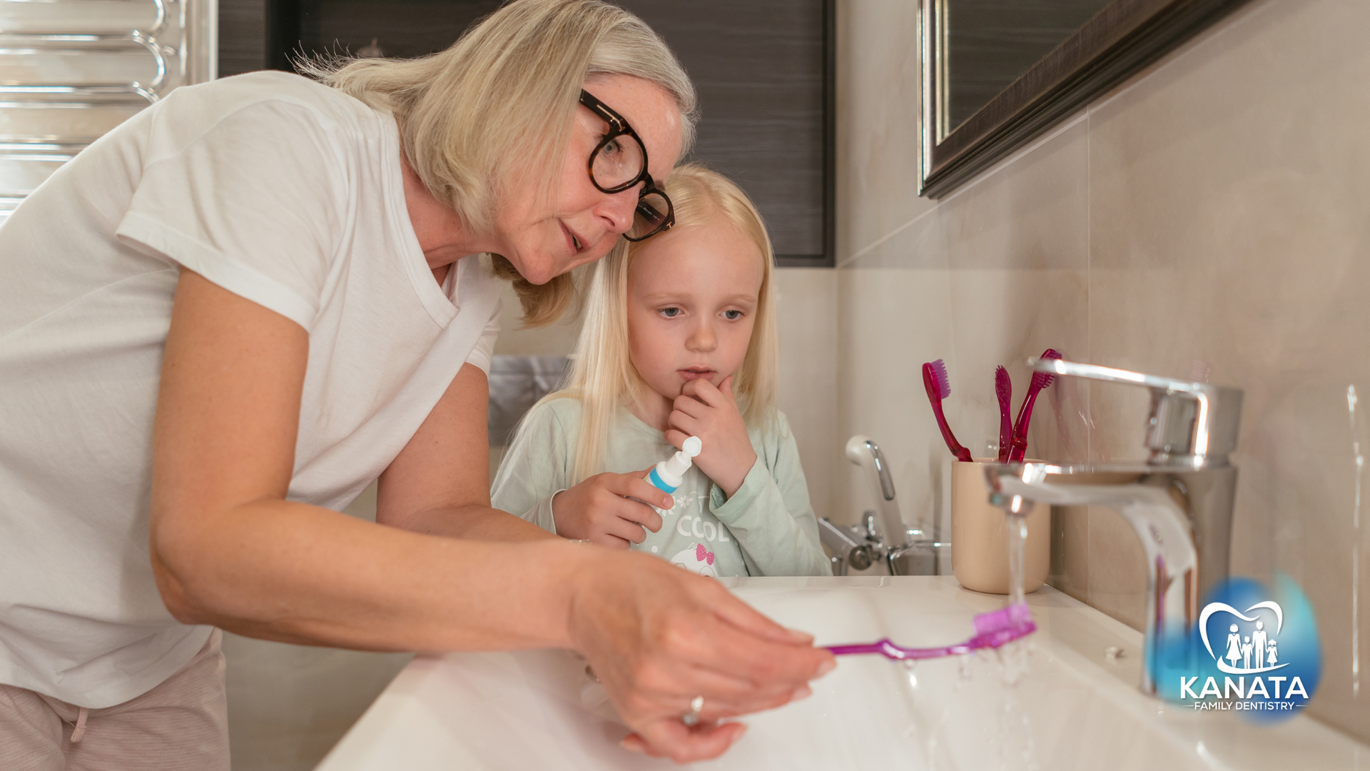 A woman and a little girl are brushing their teeth in a bathroom.