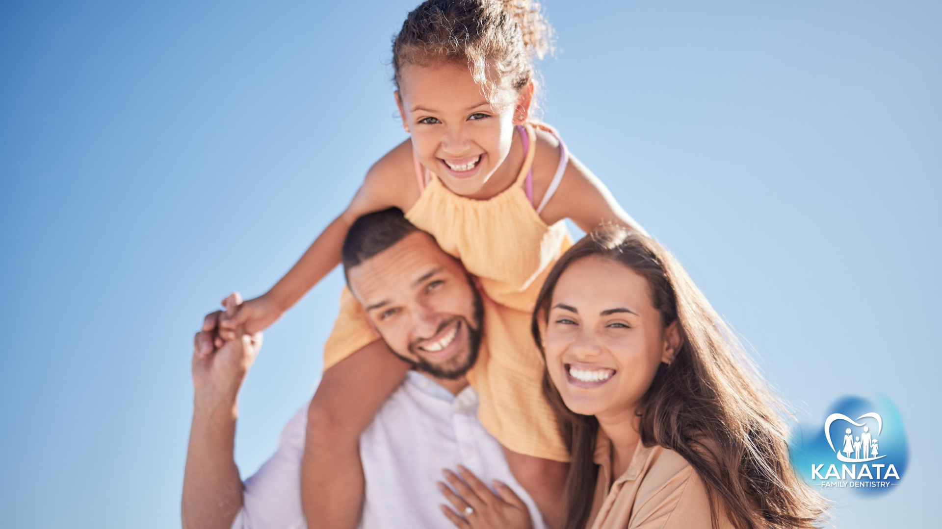 A man and woman are holding a little girl on their shoulders.