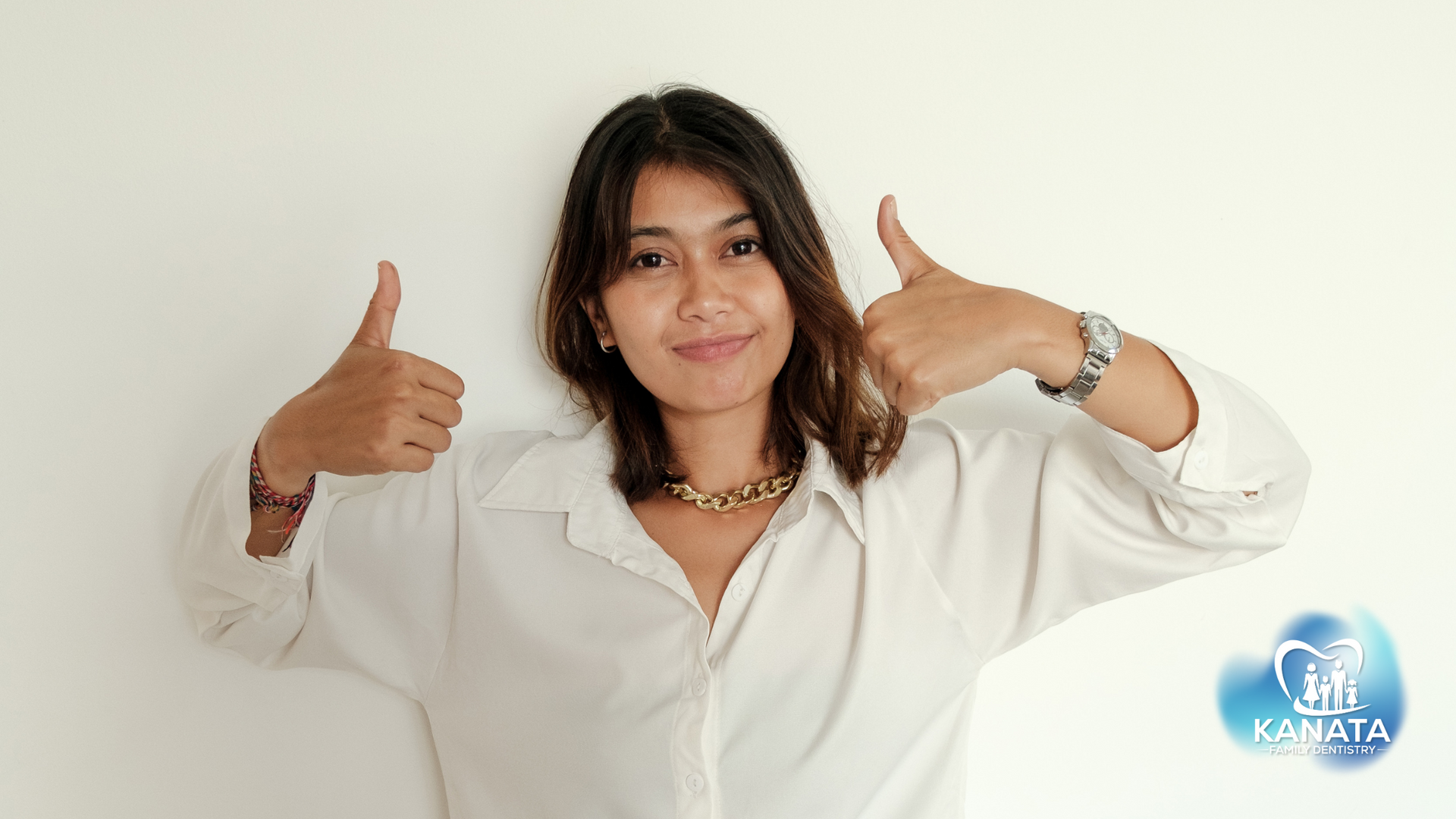 A woman in a white shirt is giving two thumbs up.