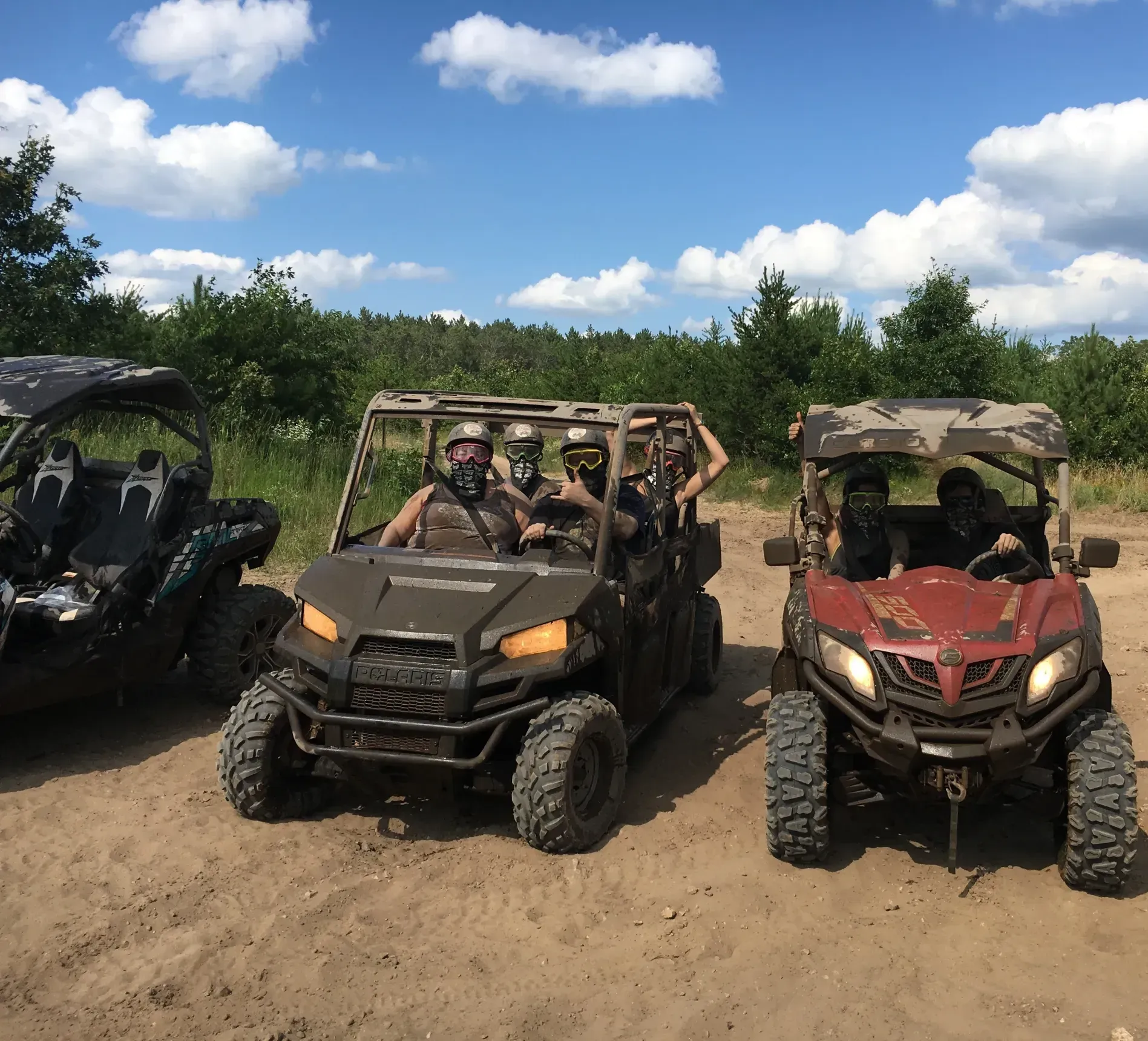 Three atvs are parked next to each other on a dirt road