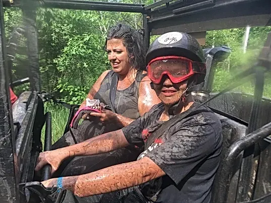 A man and a woman are sitting in a muddy vehicle.