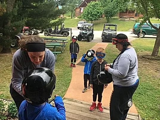 A woman is helping a young boy put on a helmet.