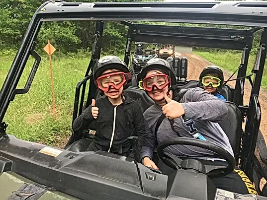 A group of people are sitting in a atv giving a thumbs up.