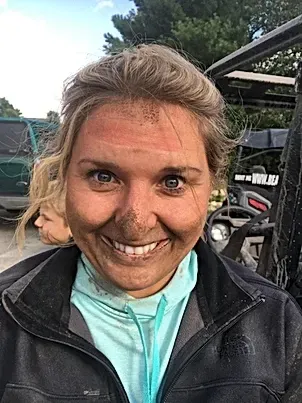 A woman with a lot of dirt on her face is smiling.