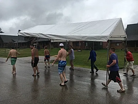 A group of men are walking in the rain under a tent.