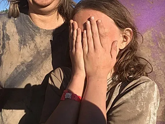 A woman and a girl are covering their faces with their hands.