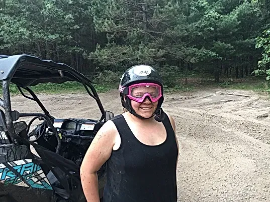 A woman wearing a helmet and goggles is standing in front of a buggy.