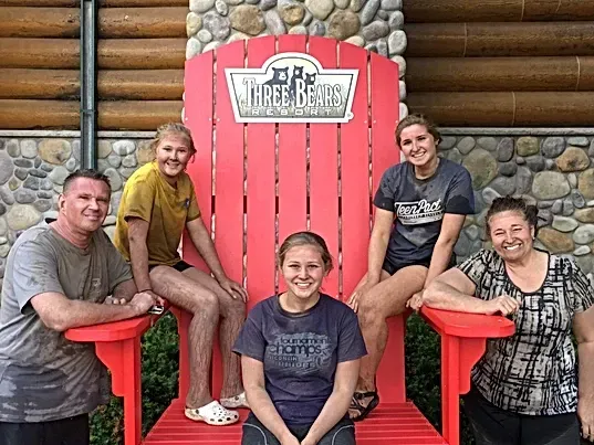 A group of people are sitting in a large red chair.