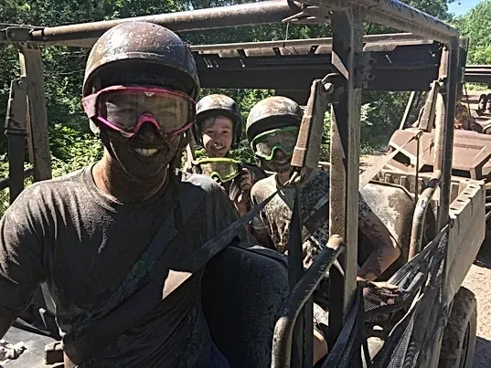 A group of people are sitting in a muddy vehicle.