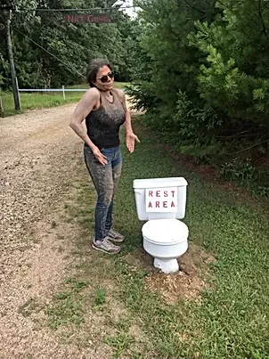 A woman is standing next to a toilet that says rest area.