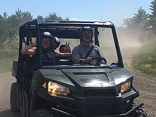 A group of people are riding a atv on a dirt road.