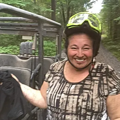 A woman wearing a helmet and goggles is standing next to a vehicle.