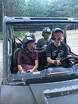 A group of people are riding in a atv on a dirt road.