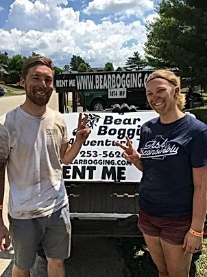 A man and a woman are standing next to each other in front of a truck.