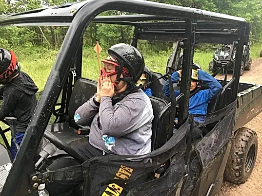 A group of people are riding atvs on a dirt road.