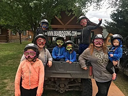 A group of people are posing for a picture in front of a atv.
