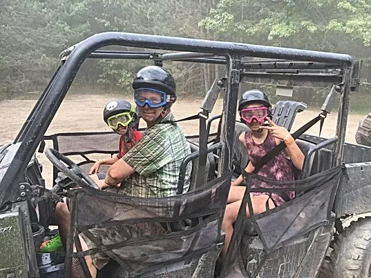 A man and two children are sitting in a atv.