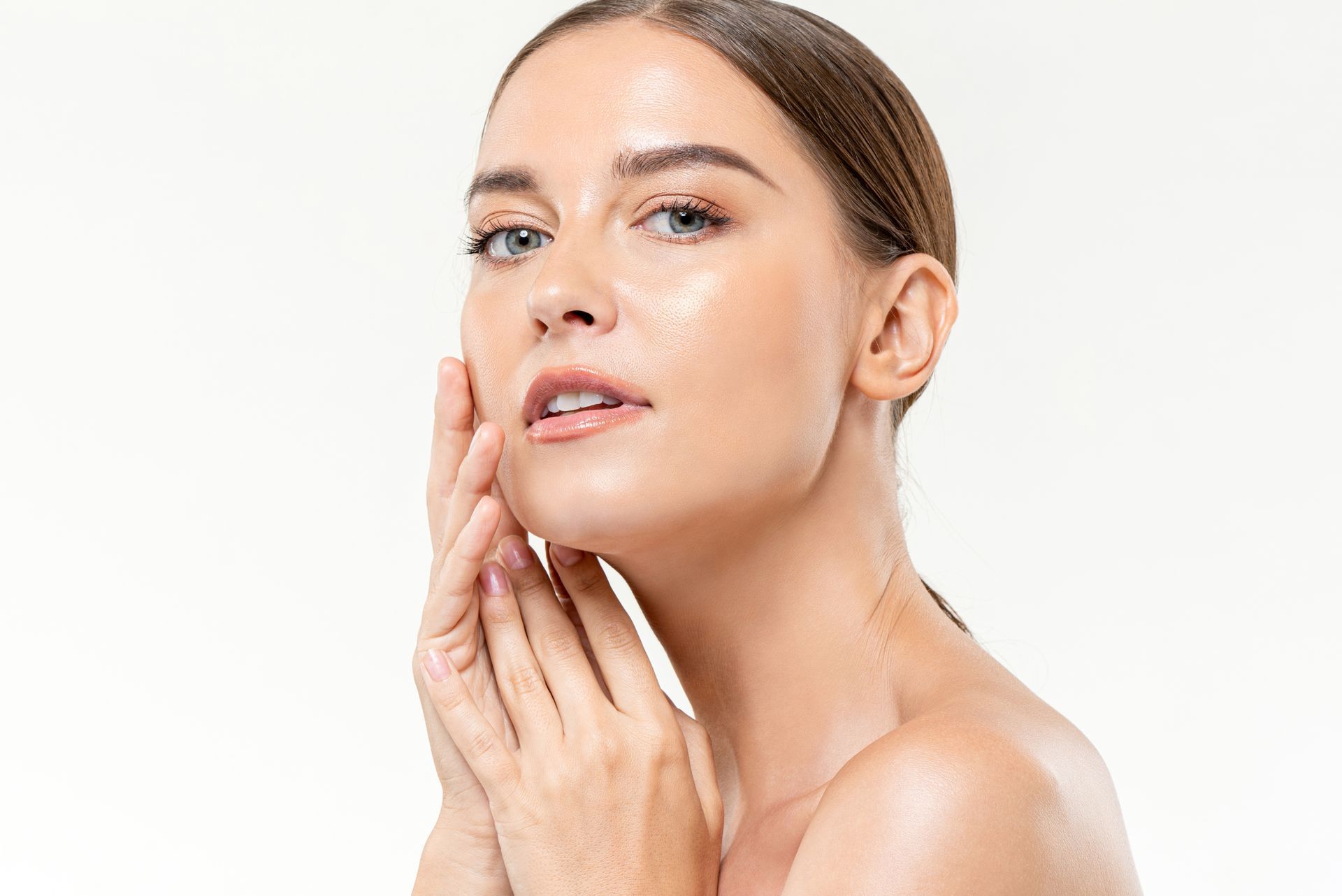 Woman with fair skin, lightly touching her face, looking at the camera.