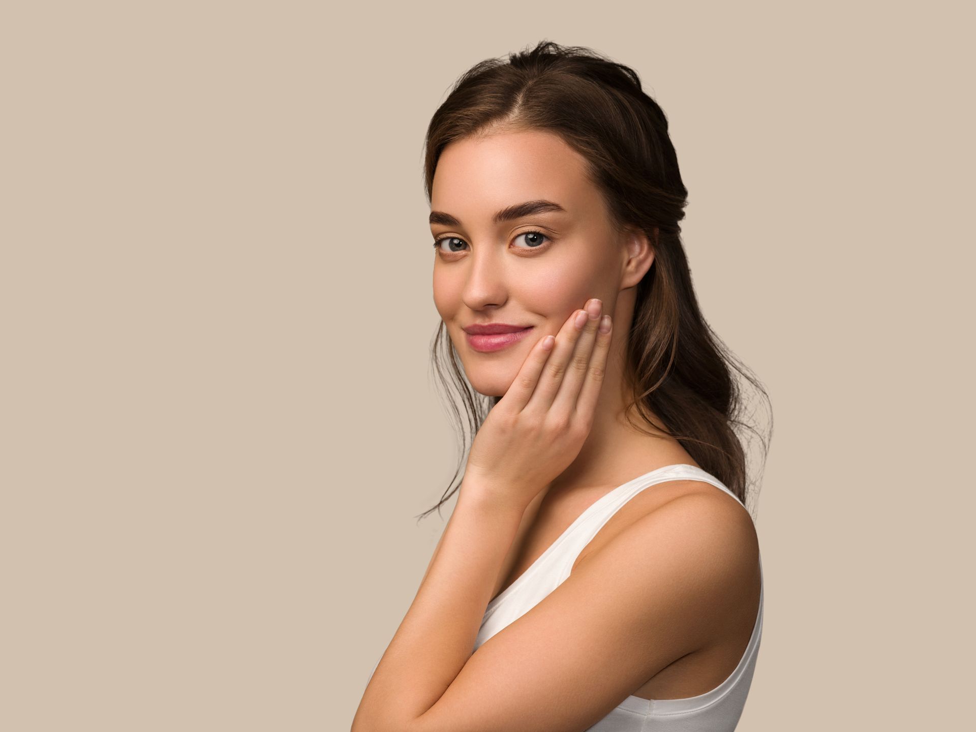 A woman is touching her face with her hand and smiling.