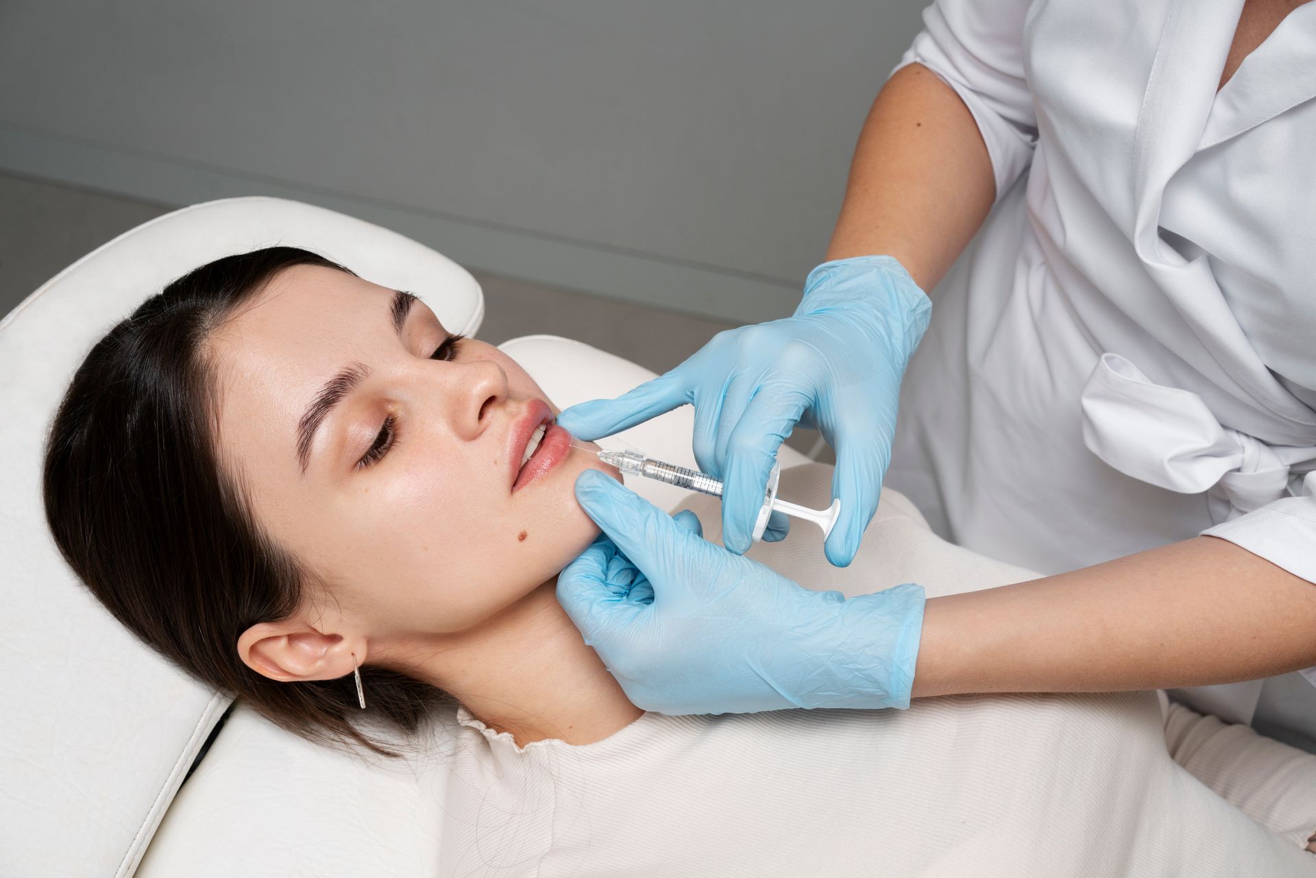 A woman is getting a botox injection in her lips.