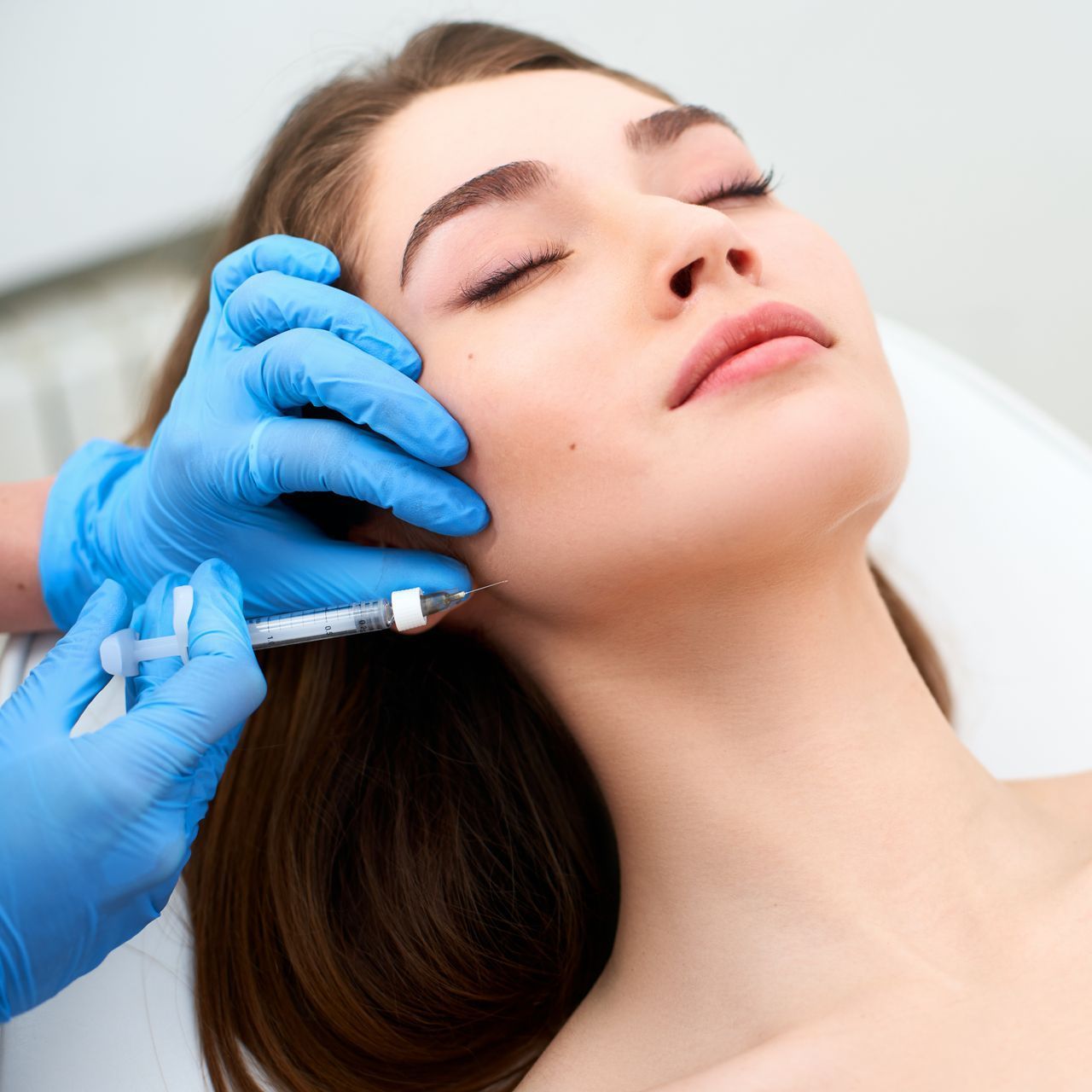 A woman is getting a botox injection in her face.