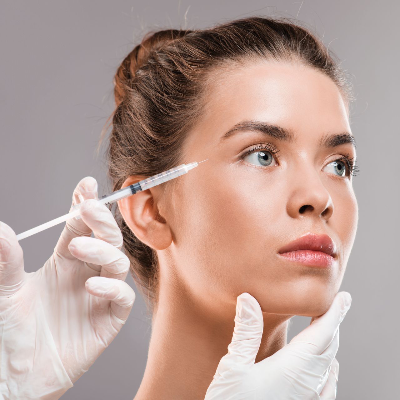 A woman is getting a botox injection in her face.