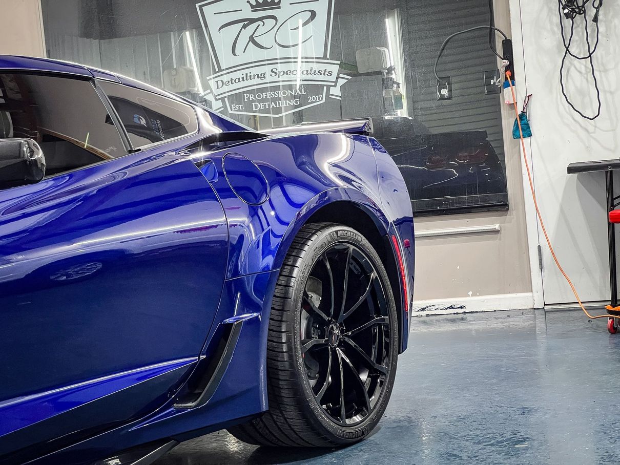 Blue sports car with black wheels in a garage, reflective paint.