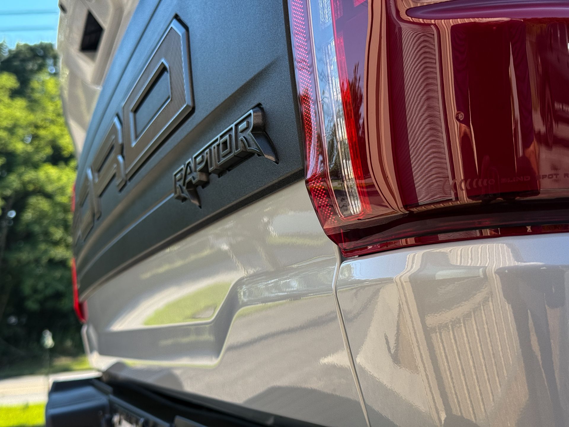 Close-up of a white Ford Raptor truck bed with red taillight and black Raptor emblem.