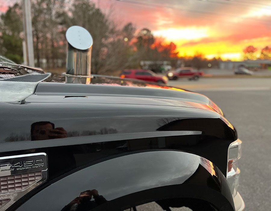 Black pickup truck with chrome exhaust stack; sunset in the background.