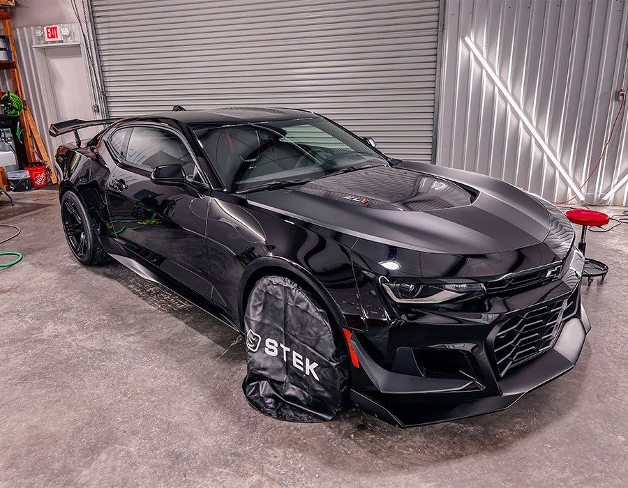 Black Chevy Camaro inside a garage, with wheel covers.