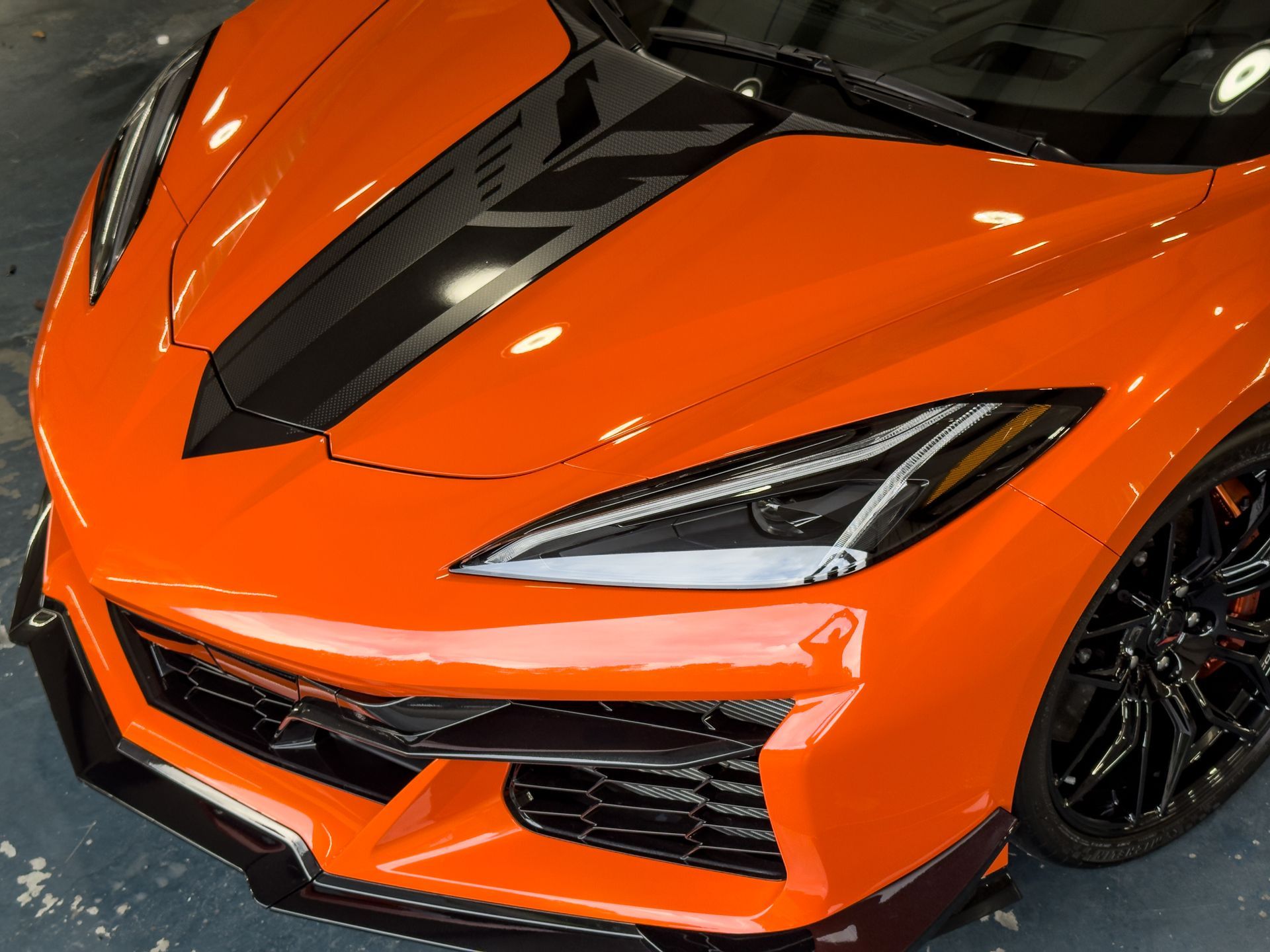 Orange sports car with black racing stripe on hood.