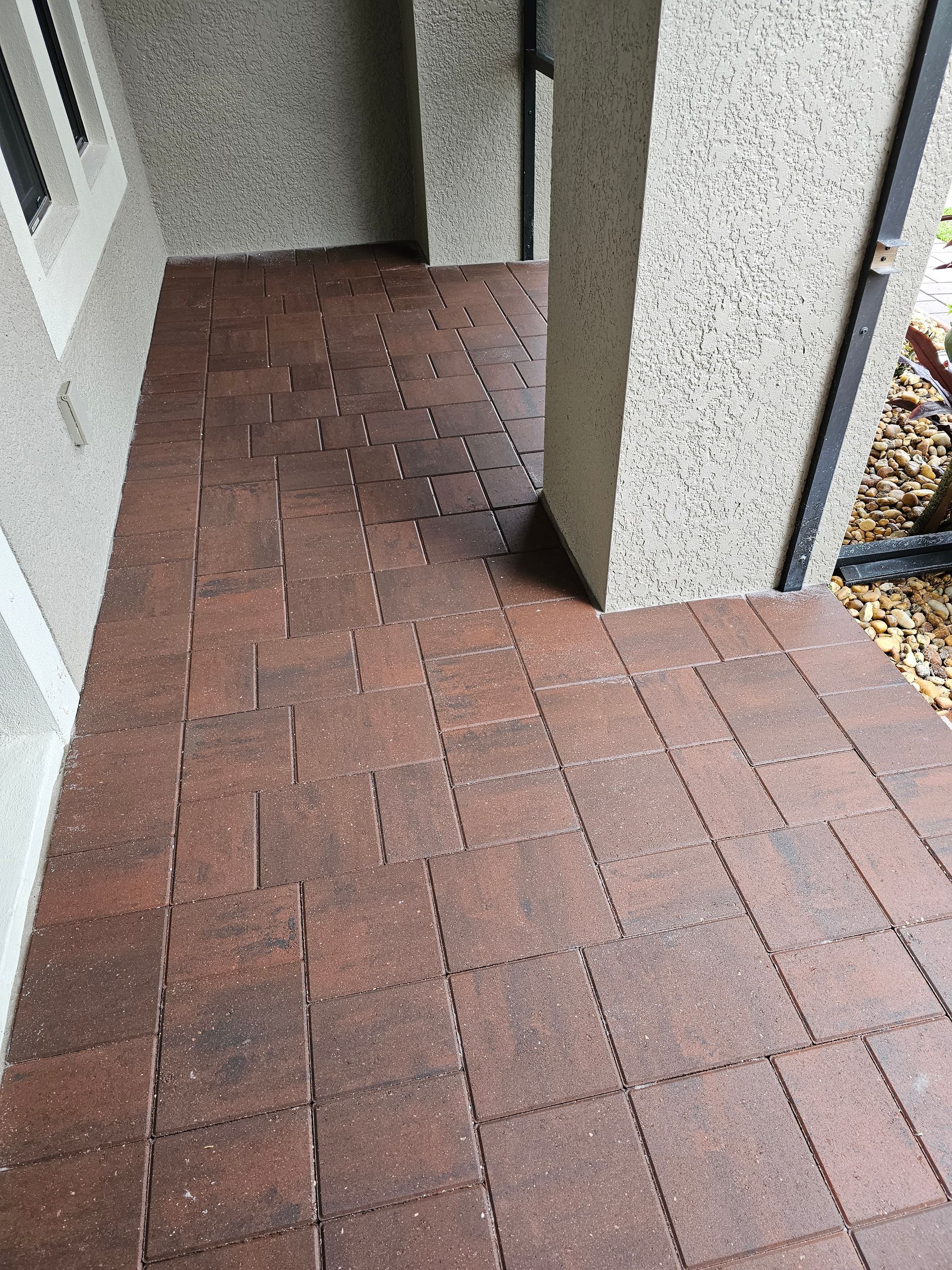 Red brick-patterned tiles on a porch floor. The tiles are arranged in a grid pattern, leading to a doorway.