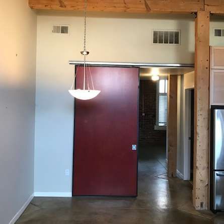 Interior view with red sliding door, pendant light, exposed brick, and concrete floor.