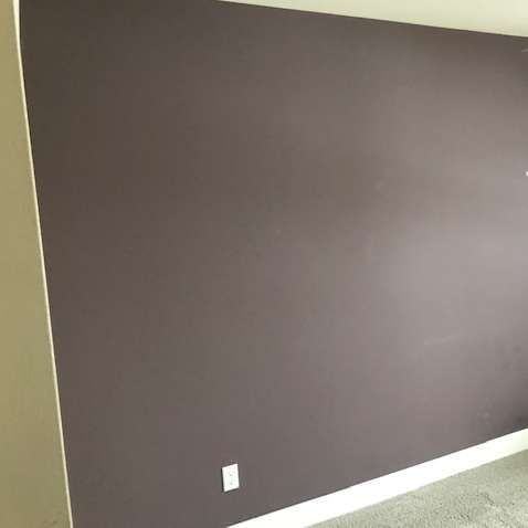 A painted dark purple wall with white trim and a white electrical outlet.