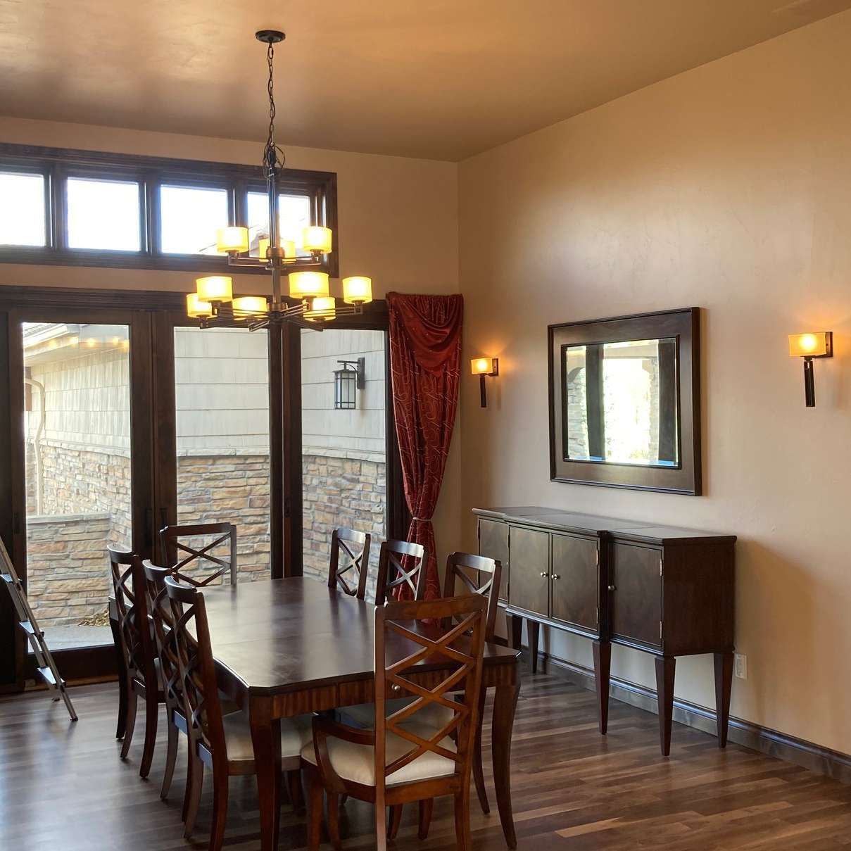 Dining room with long wooden table and chairs, buffet, and chandelier.