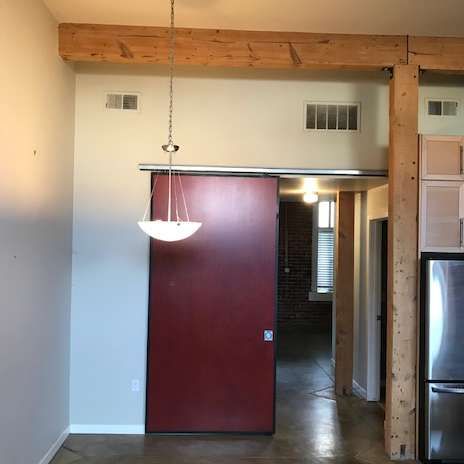 Interior view with red sliding door, wood beams, and recessed lighting.
