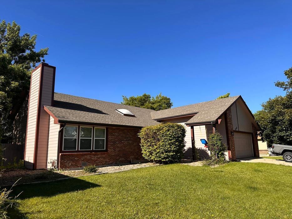 A single-story house with a brick facade, chimney, and garage under a clear blue sky.