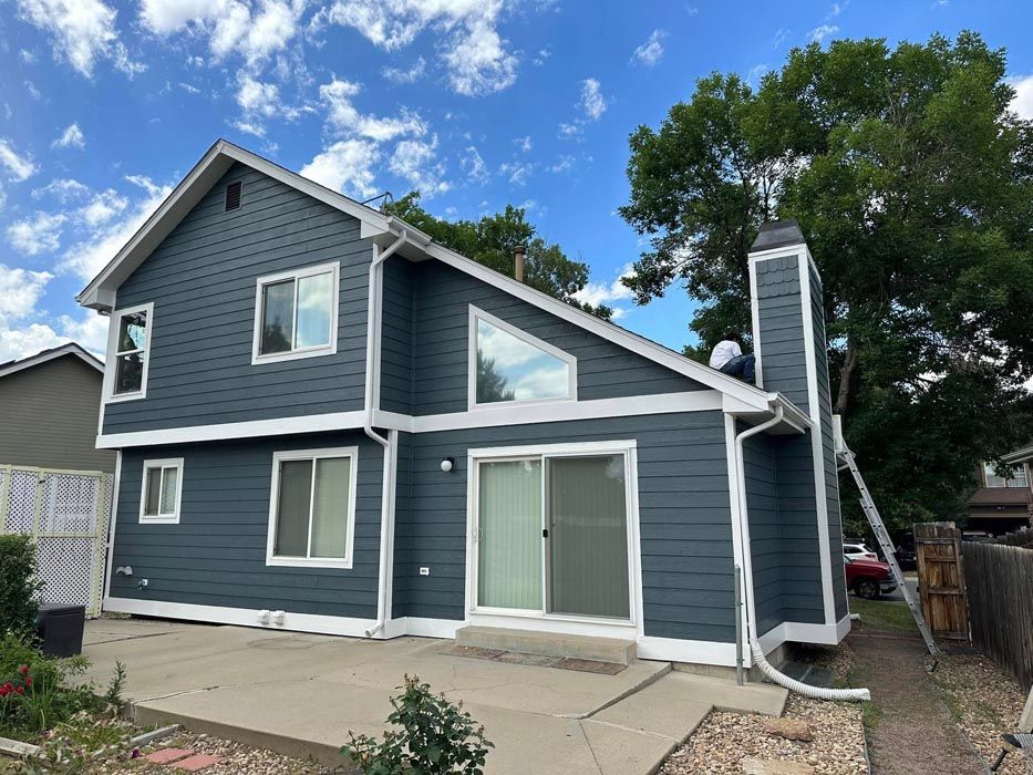 House exterior painted dark blue with white trim, clear sky.