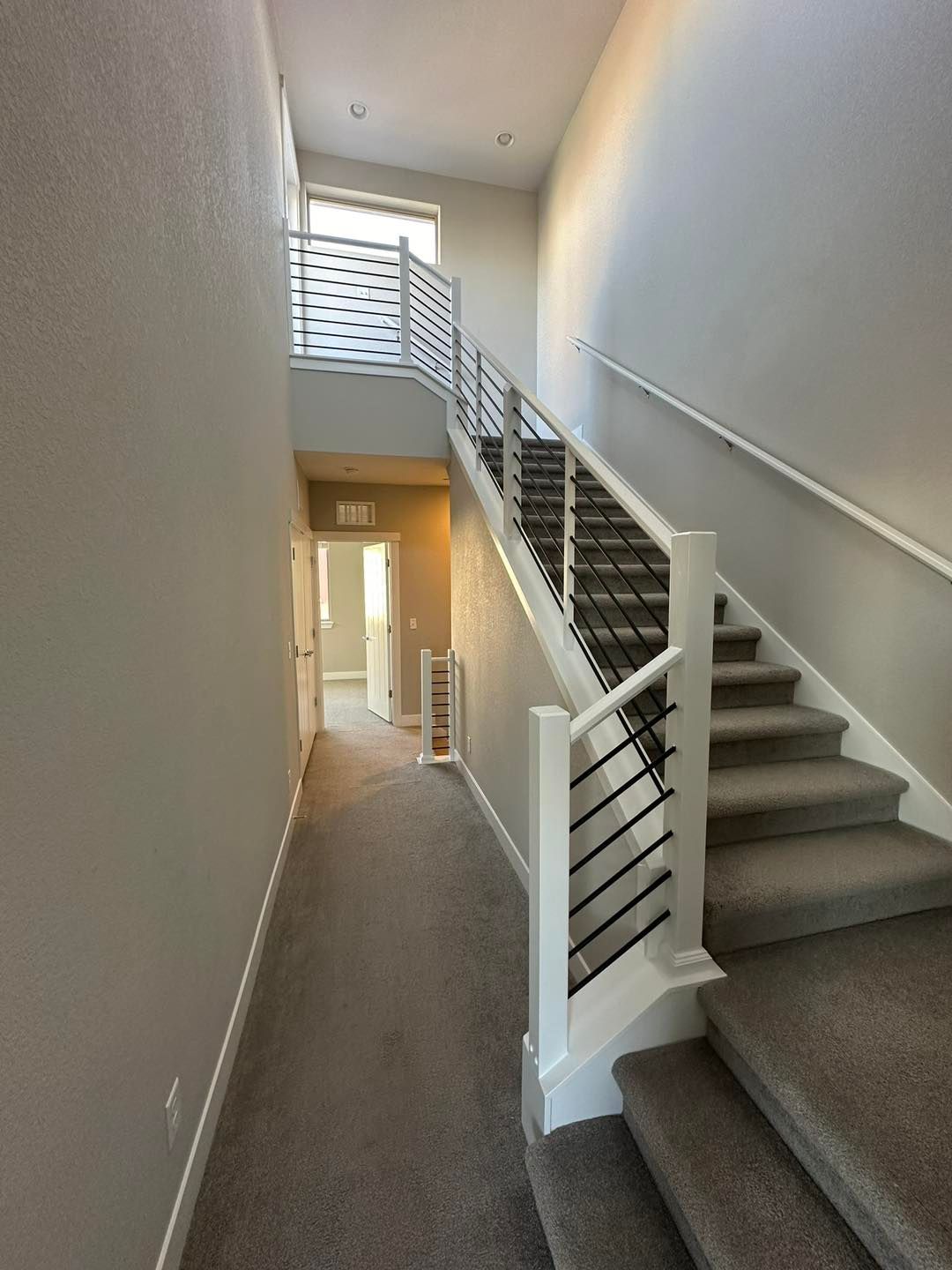 Interior view of a staircase with carpeted steps and a modern metal railing.