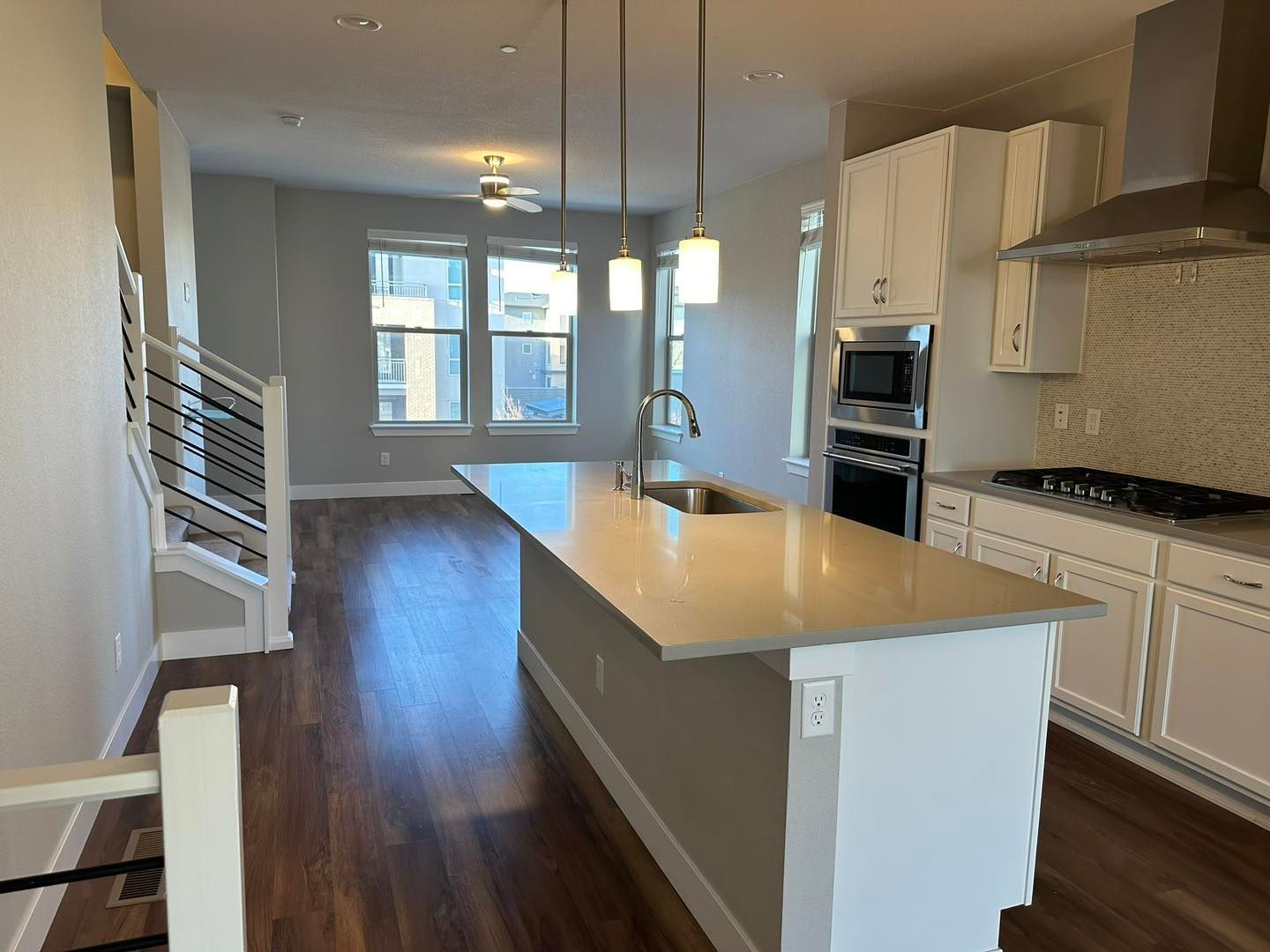 Modern kitchen with white cabinets, island, stainless steel appliances, and dark hardwood floors.