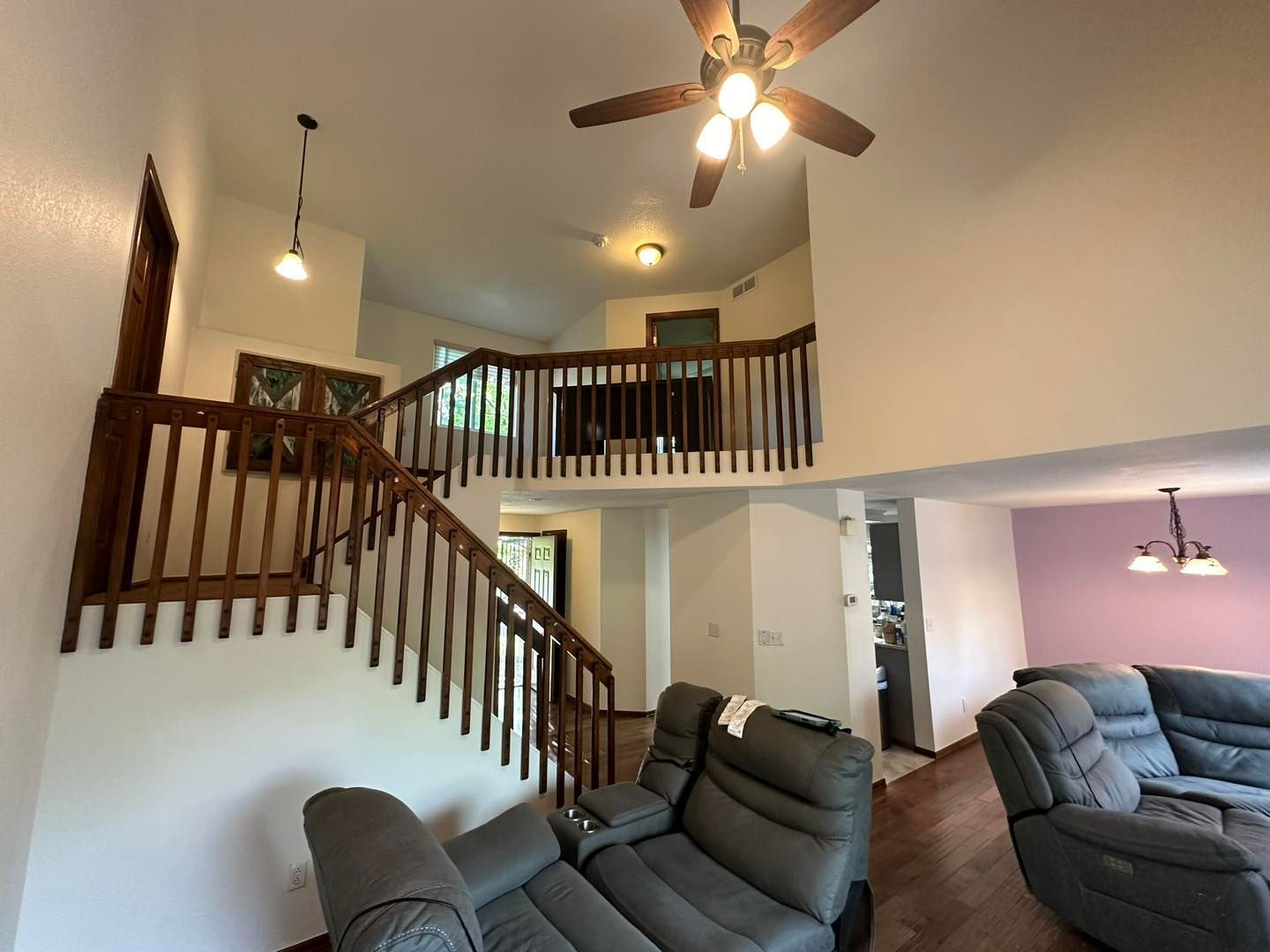 Interior view of a two-story home with a staircase, loft, and reclining sofa.
